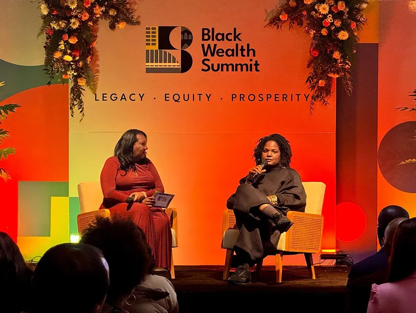 Two women sit on stage for a talk at a Black Wealth Summit.